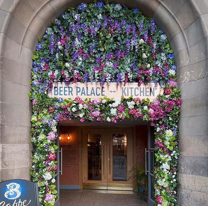 Floral archway bursting with colourful artificial flowers and lush greenery welcomes guests at Brewhemia Edinburgh