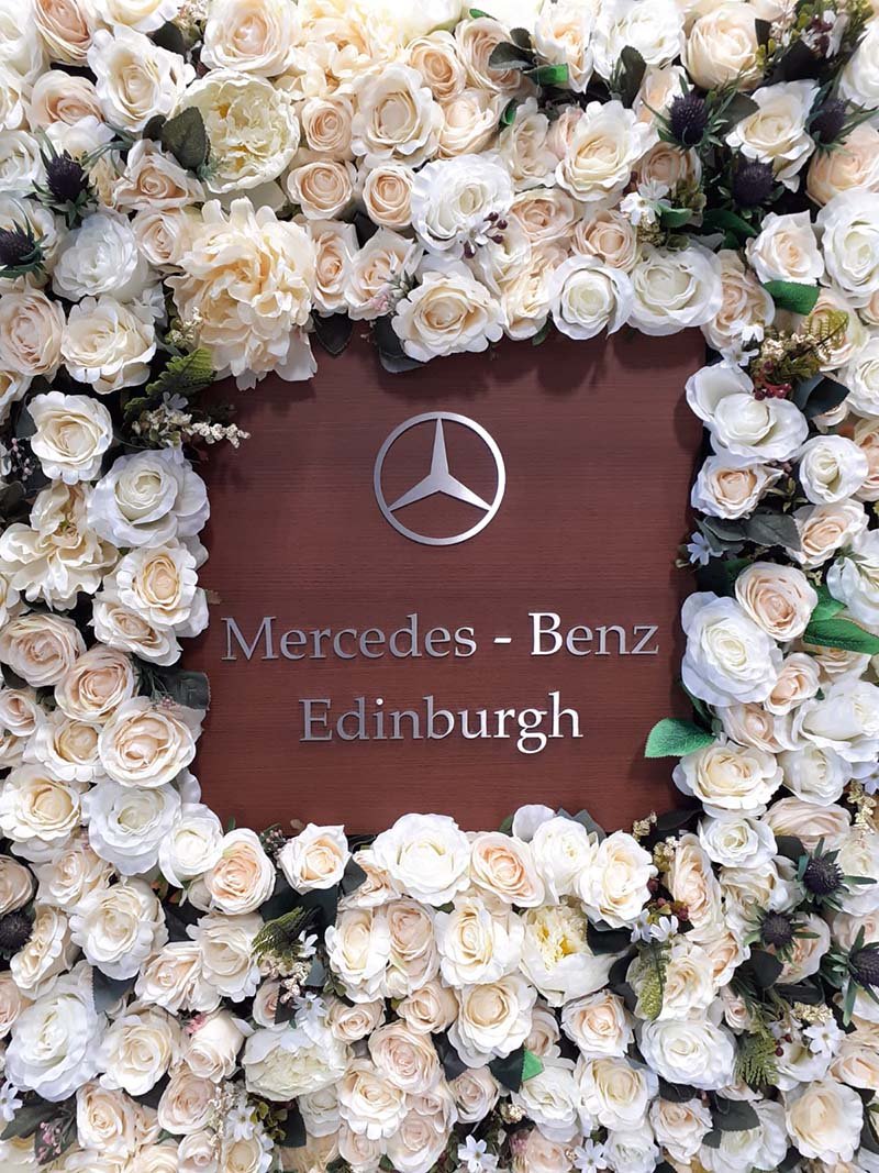 Bespoke branded artificial rose and thistle floral wall for Mercedes Benz Edinburgh car showroom handover area
