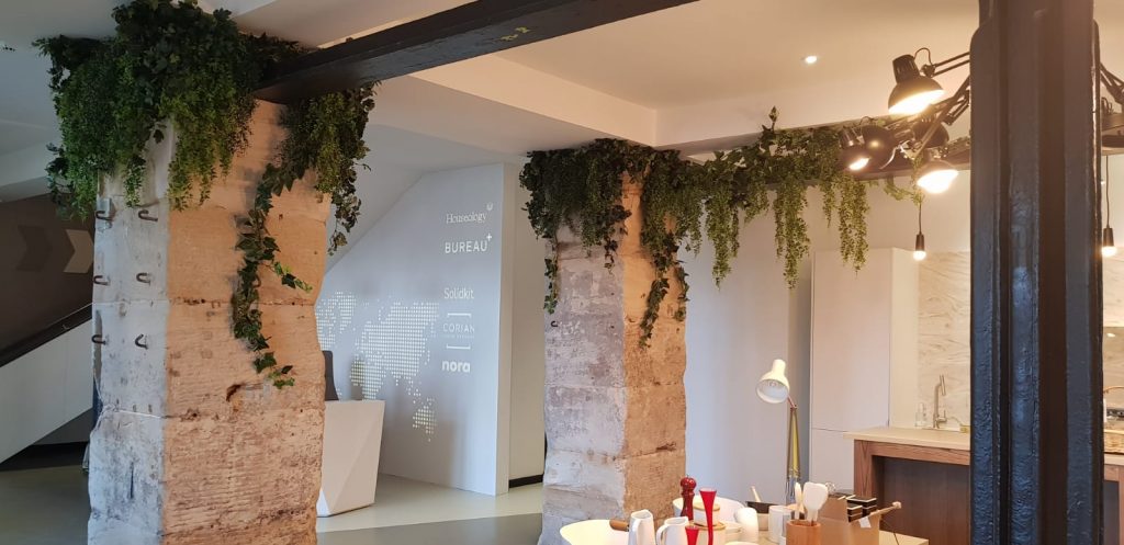 Traditional stone columns and exposed beams in converted offices draped with ivy and foliage make it warm and welcoming