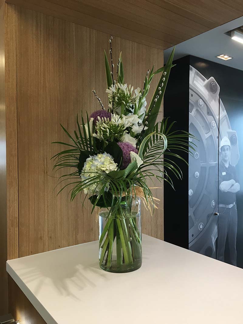 A commercial fresh flower arrangement in glass vase on reception desk provides a warm welcome to visitors