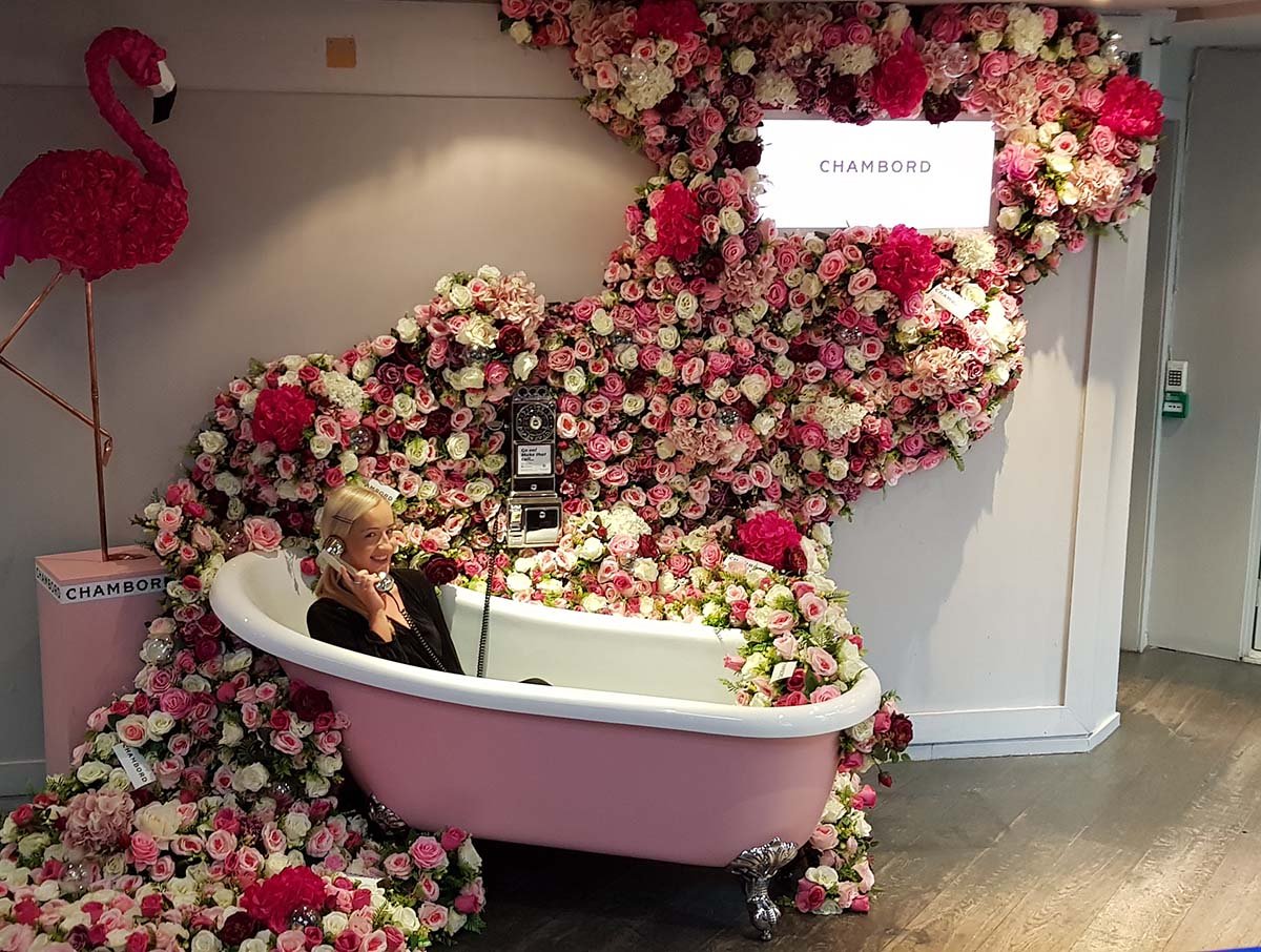 October’s Ultimate Chambord selfie spot! Woman in vintage bath overflowing with pink and white roses, fun phone, flamingo