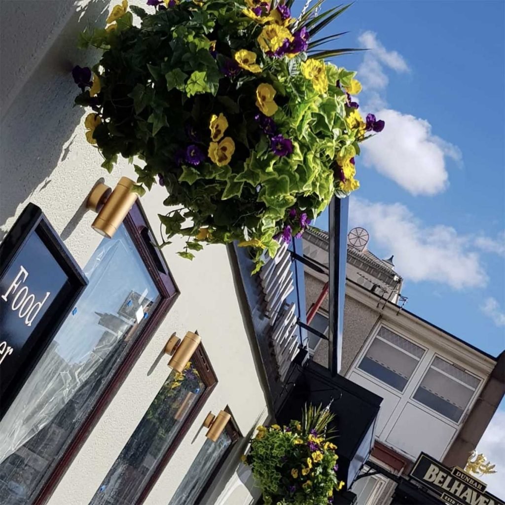 Beautiful hanging baskets in full bloom with yellow pansies and trailing foliage for a restaurant exterior