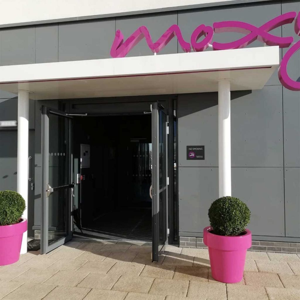 Moxy hotel Edinburgh Airport with oversized bubblegum pink planters filled with manicured buxus balls
