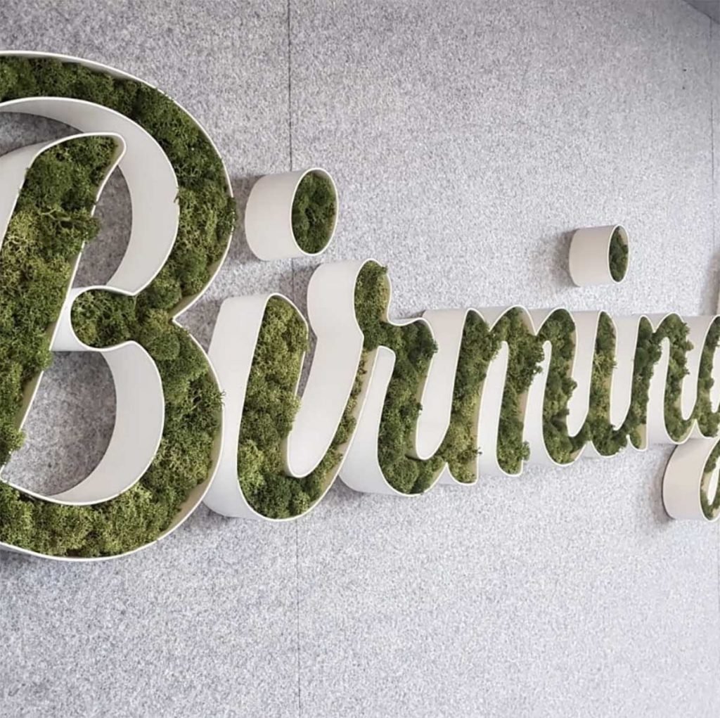 Bespoke made letter frames of green Nordik Moss to spell Birmingham on grey wall