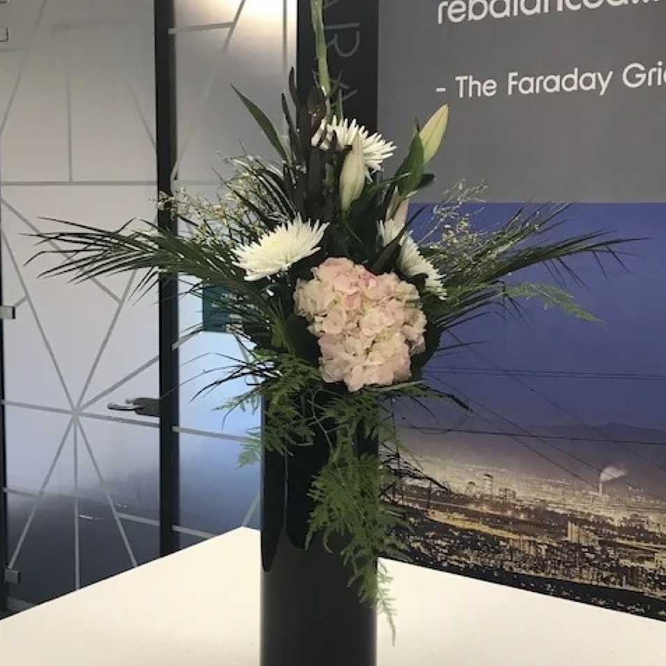 White lilies, and hint of pink hydrangea in a tall slim vase black vase with greenery for Faraday Grid Edinburgh