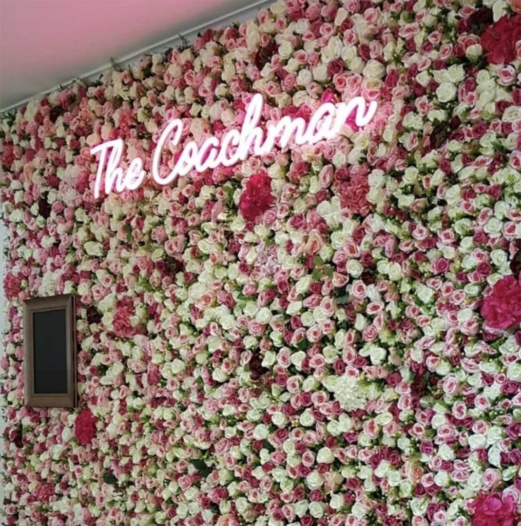 The Coachman, Kilsyth and their bespoke selfie wall of artificial roses and hydrangea with a neon sign and blackboard