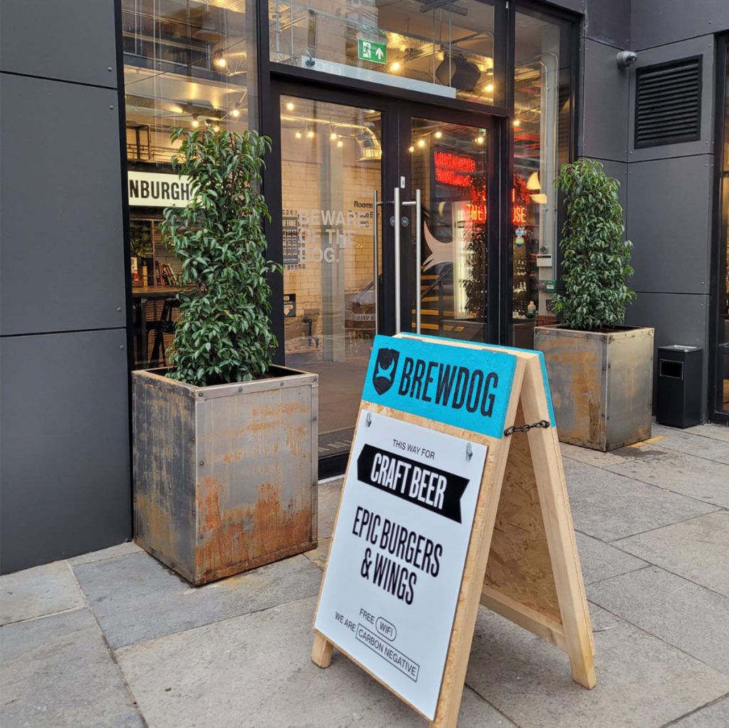 Live Buxus pyramid plants inside aged lead effect planters give the perfect rustic vibe to the BrewDog Edinburgh entrance.