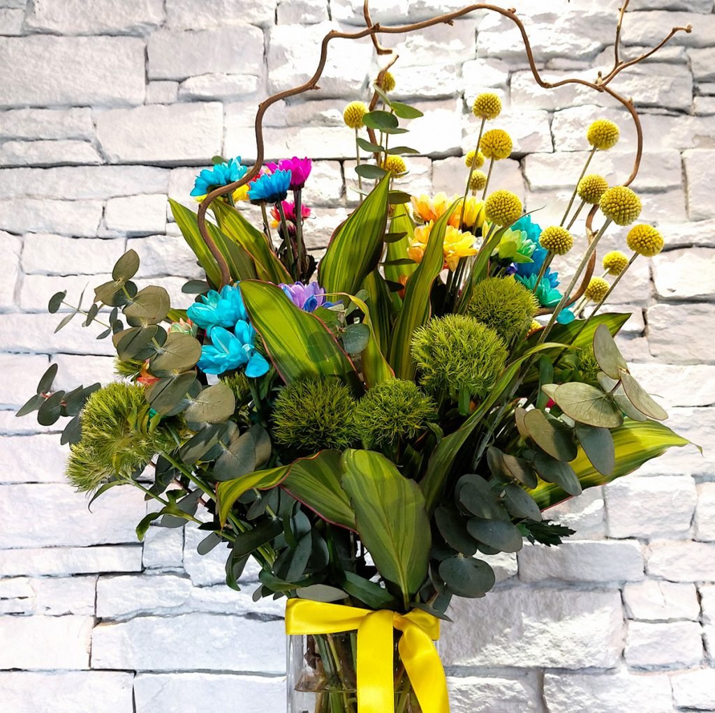a beautiful display featuring rainbow chrysanthemums, yellow craspedia, and eucalyptus