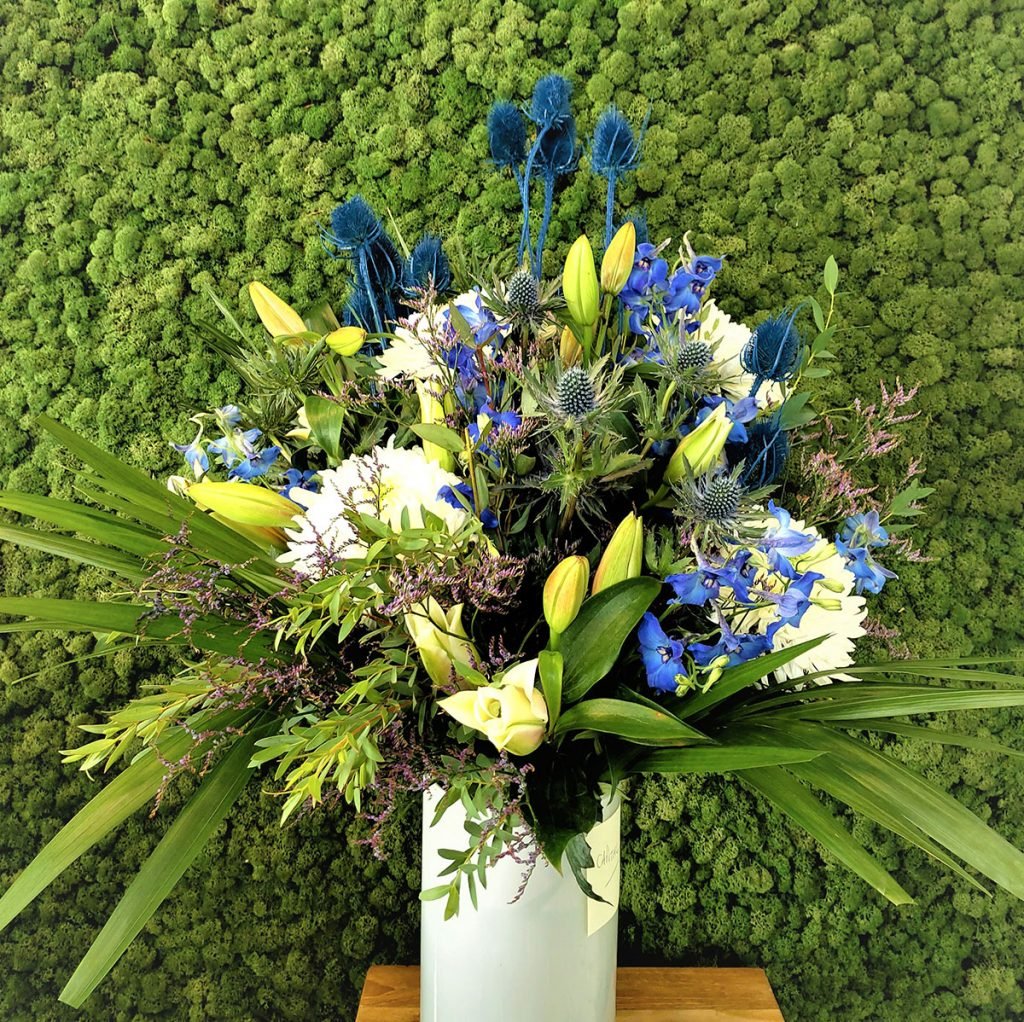 white vase with a scottish theme display featuring white blooms, thistles and white lilies