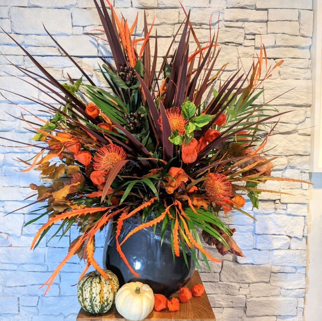 spectacular halloween themed corporate flower display featuring chinese lanterns, cordyline, leucospernum, autumn leaves and pumpkins