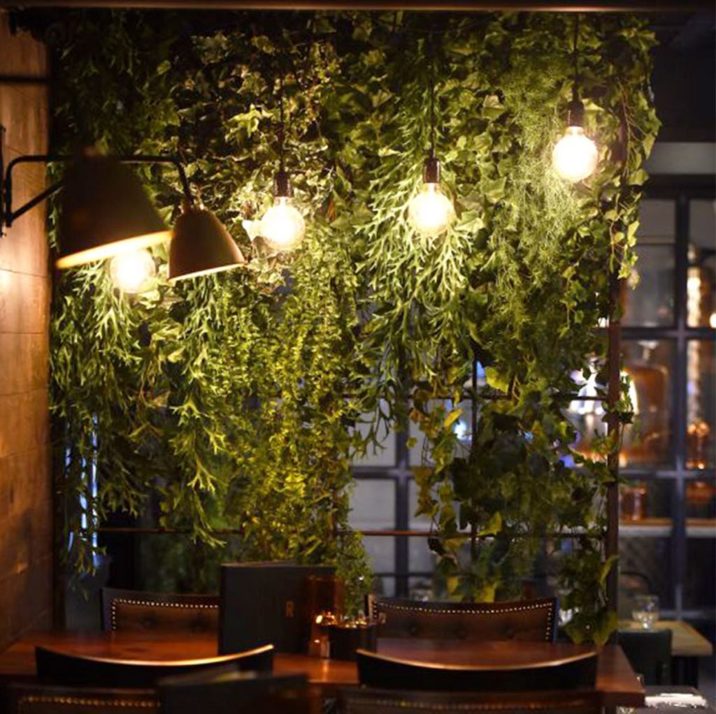 green artificial plants cascade down this interior trellis divider to add subtle colour and a beautiful touch of nature in this dark atmospheric interior
