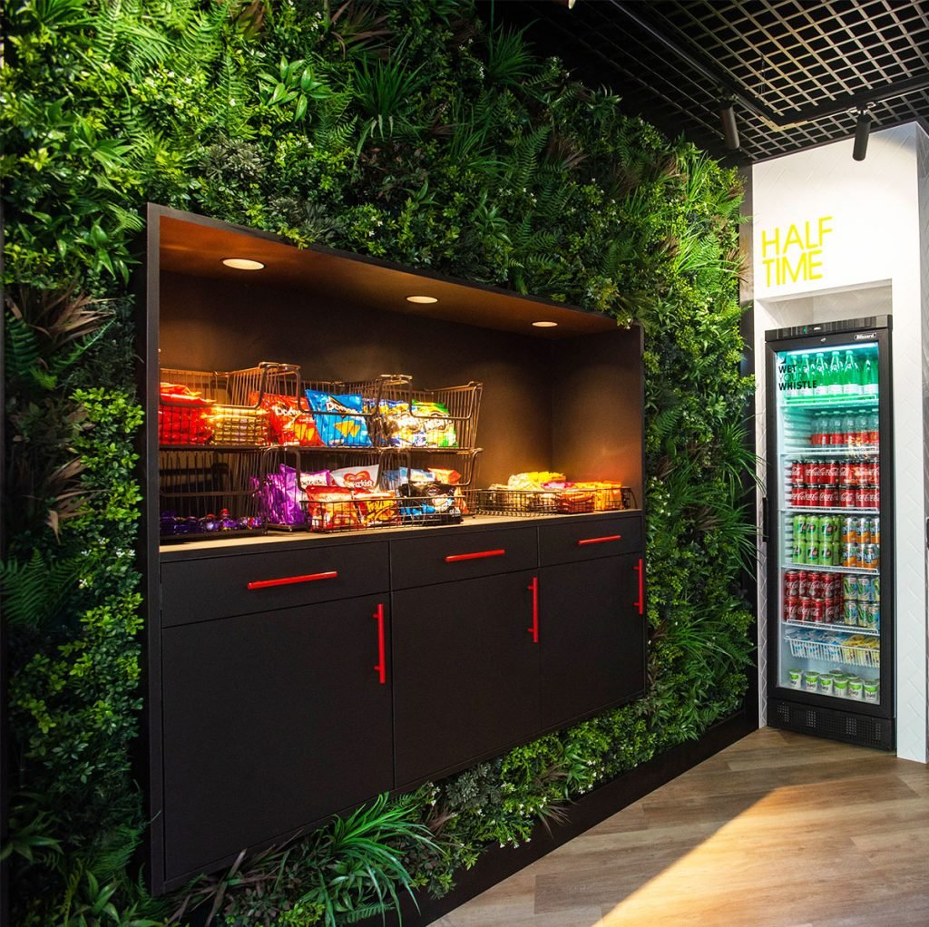 stunning green wall created with artificial plants to create an inviting base for the snacks station at the Arsenal football club kitchen