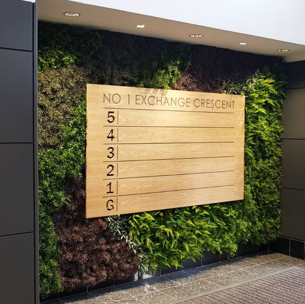 this artificial green wall makes a beautiful impact in the entryway of this office building - the striped design gives it added flair
