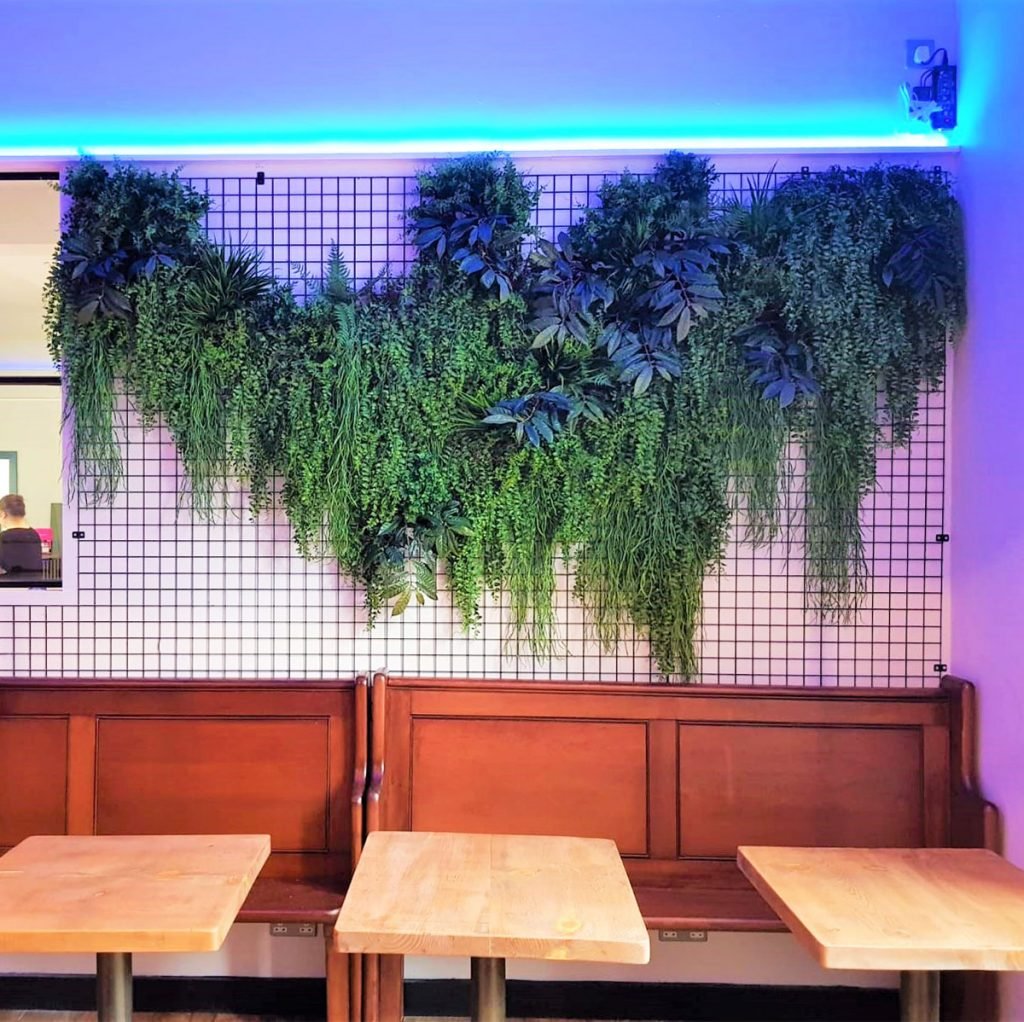 artificial trailing ivy bushes cascading down a mesh panel fixed to the wall