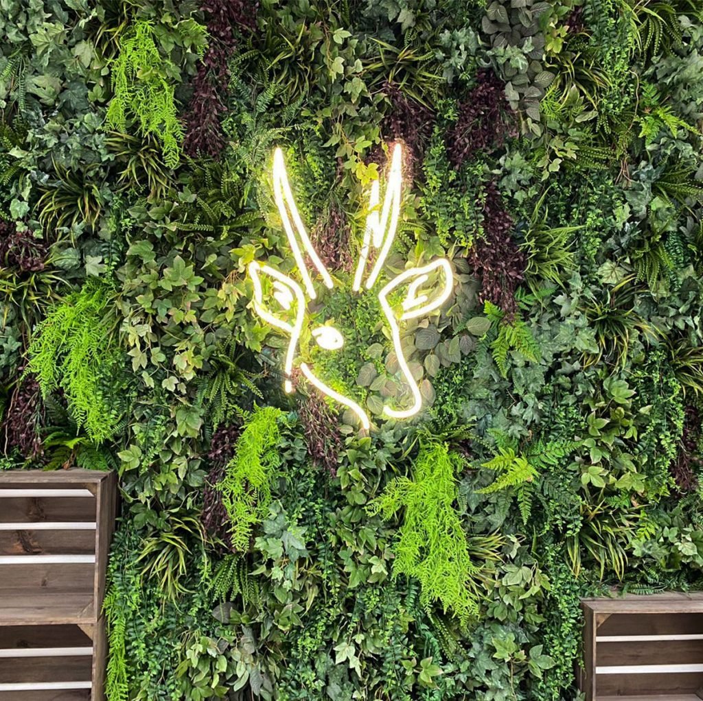 bespoke built artificial green wall with neon signage makes a statement on the wall at the Archerfield Estate in Edinburgh