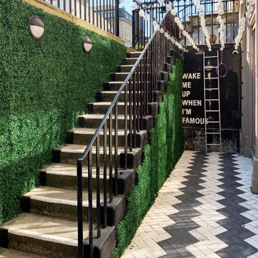 simple artificial green wall creates a soft natural impact on this staircase wall.