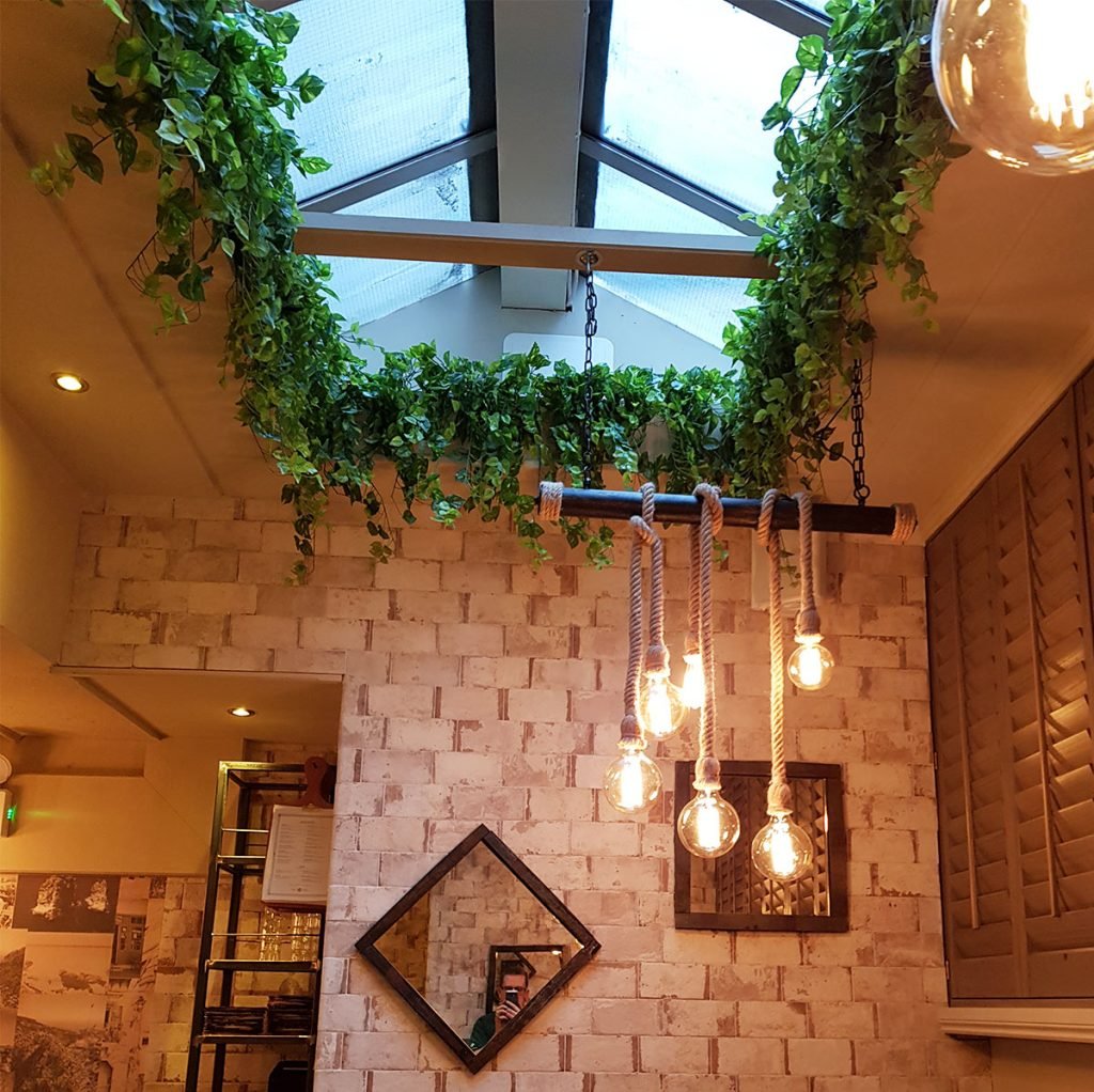 artificial trailing plants line this skylight and enhance the rustic vibe within this beautiful restaurant