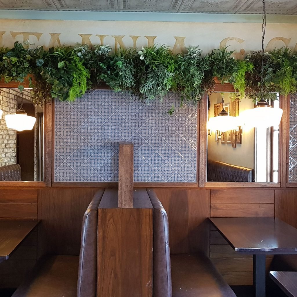 green trailing plants add interesting texture and colour in this restaurant interior and look great paired with the wooden furniture.