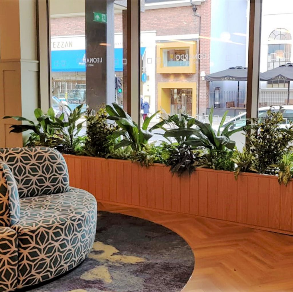 artificial mixed plants set within an inbuilt planter under the window in a restaurant
