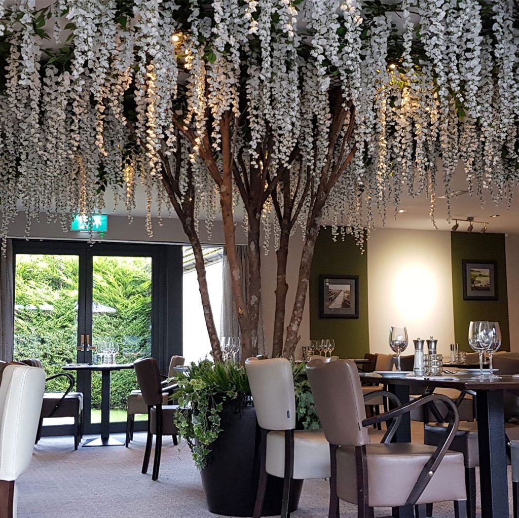 beautiful bespoke built white wisteria tree, planted in a round pot in the middle of the room and spanning the ceiling in all directions to hang over the tables in the restaurant