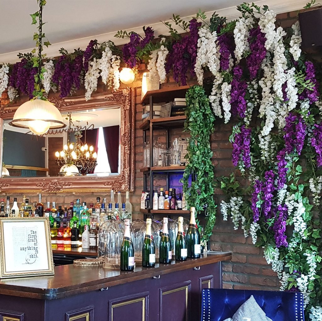 bespoke built wisteria blossom vine in purple and white, creeping over the bar and bringing in a lovely burst of colour