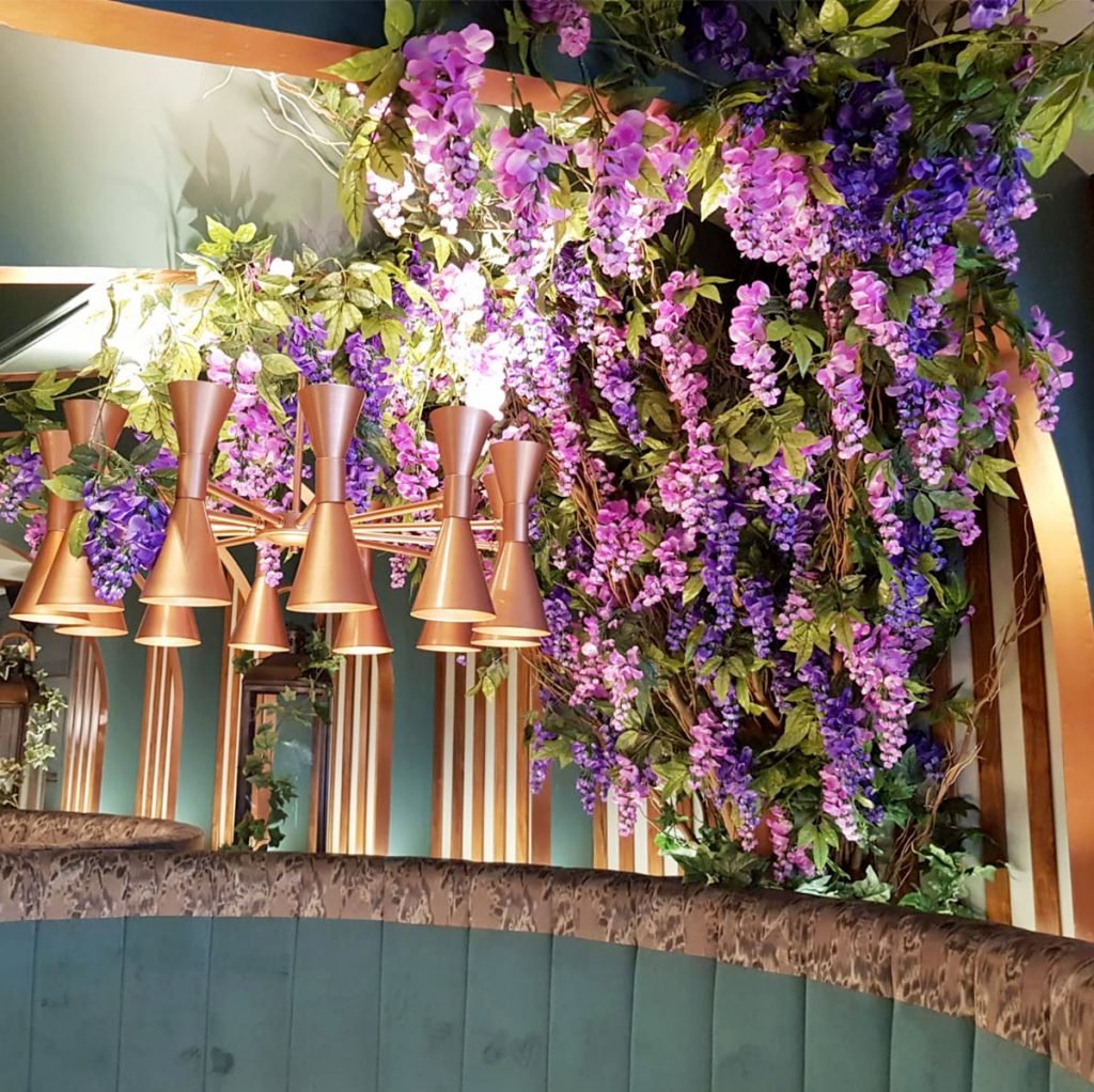 statement floral vine of purple wisteria built to creep up the wall and trail over the seating booths, creating a cosy floral nook within the grape and grain restaurant in aberdeen