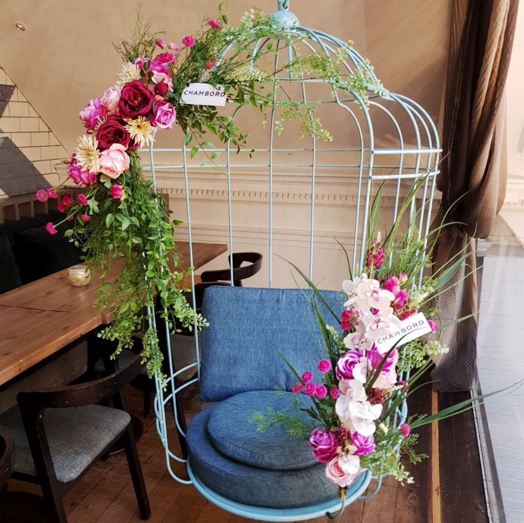 Hanging birdcage chair decorated with pink floral displays on each corner to showcase the chambord brand at the hummingbird in glasgow