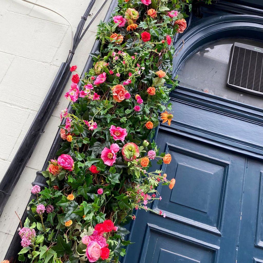 artificial summer floral display fixed around a doorway to create a feature exterior frontage outside a restaurant