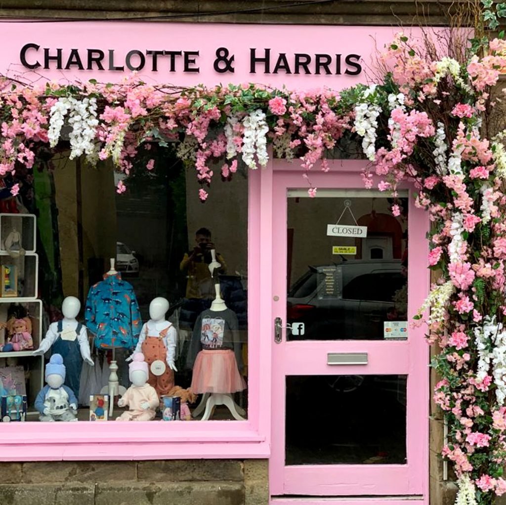 gorgeous pink and white floral display trailing across the frontage and down the side of charlotte & harris childrenswear store, perfectly matched to their exterior paint colour