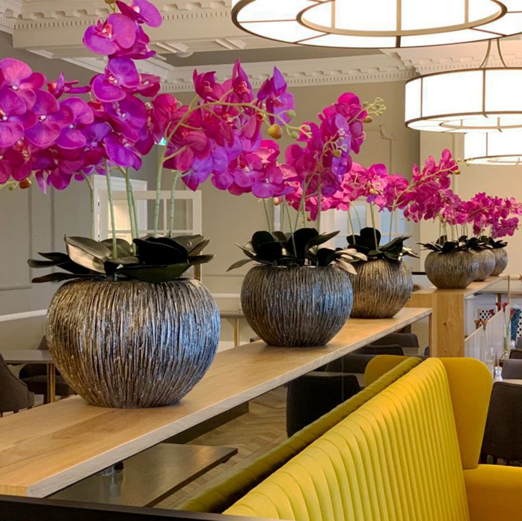 beautiful pink artificial orchids planted in unique textured bowls and set along a ledge in the restaurant at the Ro Hotel in Winderemere. long lasting alternative to fresh flowers