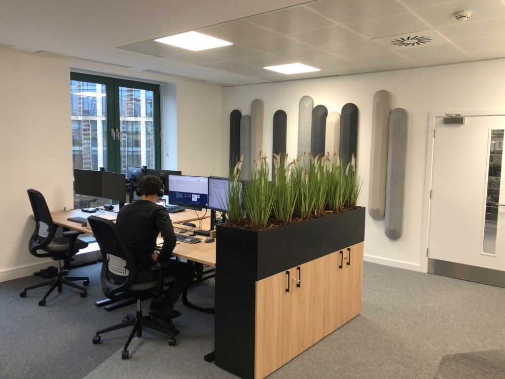 Tall artificial grass in a cabinet trough planter create a great barrier for busy employees