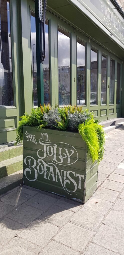 A bespoke branded exterior trough filled with mixed artificial planting is a great barrier