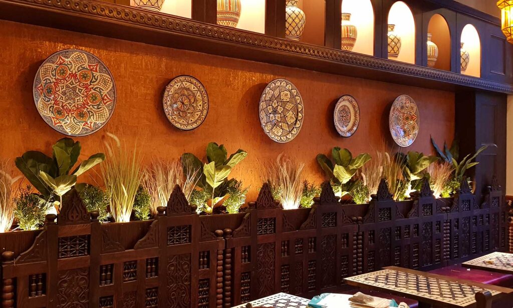 Artificial plants illuminated behind a restaurant seating booth create a unique look