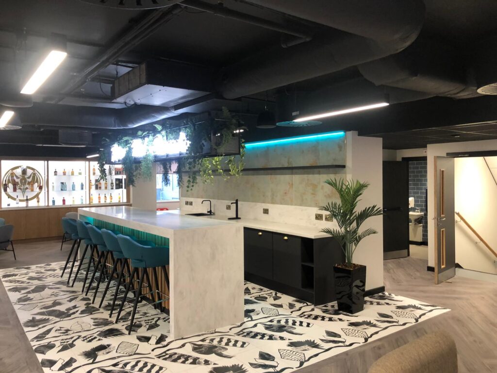 Artificial high level trailing foliage and artificial kentia palm in a black gloss planter in a corporate kitchen.