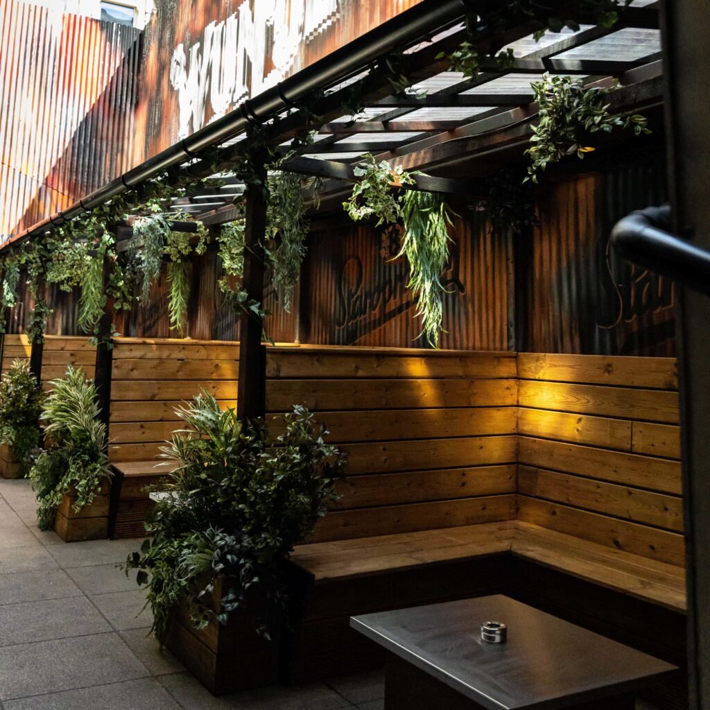 A variety of high level artificial plants trail over seating booths in wunderbar's exterior eating area