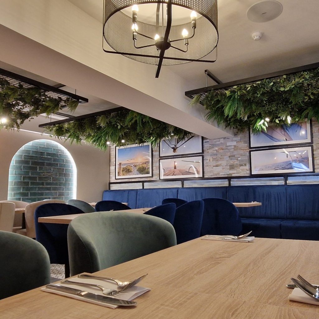 Artificial ferns and ivy fixed to a mesh ceiling grid in a communal area at solway holiday park