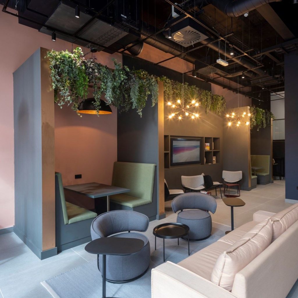 artificial trailing foliage sits atop a seating booth in a corporate space