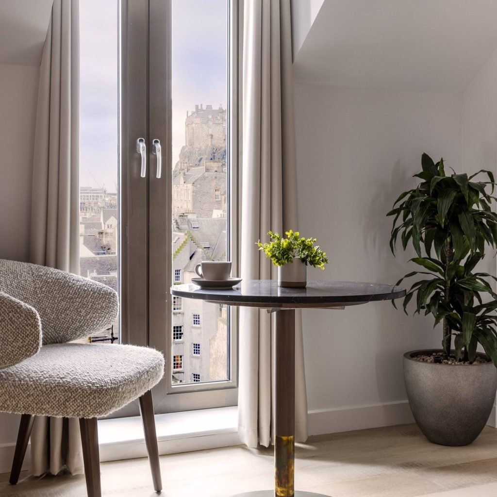 A grey ombre feature planter with a live dracaena sits in a room at the virgin hotel edinburgh, with stunning views of edinburgh castle