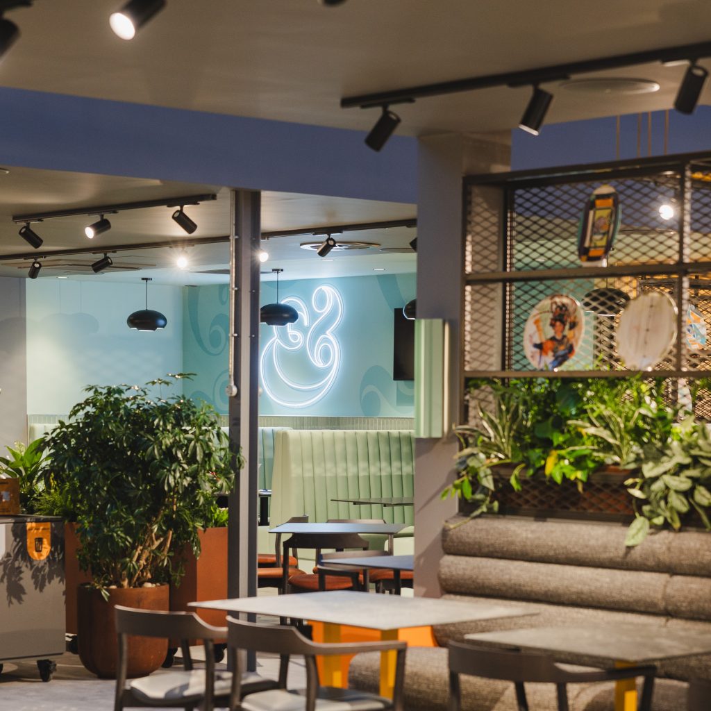 Mixed live planting with trails in trough planters line the seating booths with beautiful greenery, whilst beautiful specimen plants sit in rust effect planters in this cafe at Wellington College.